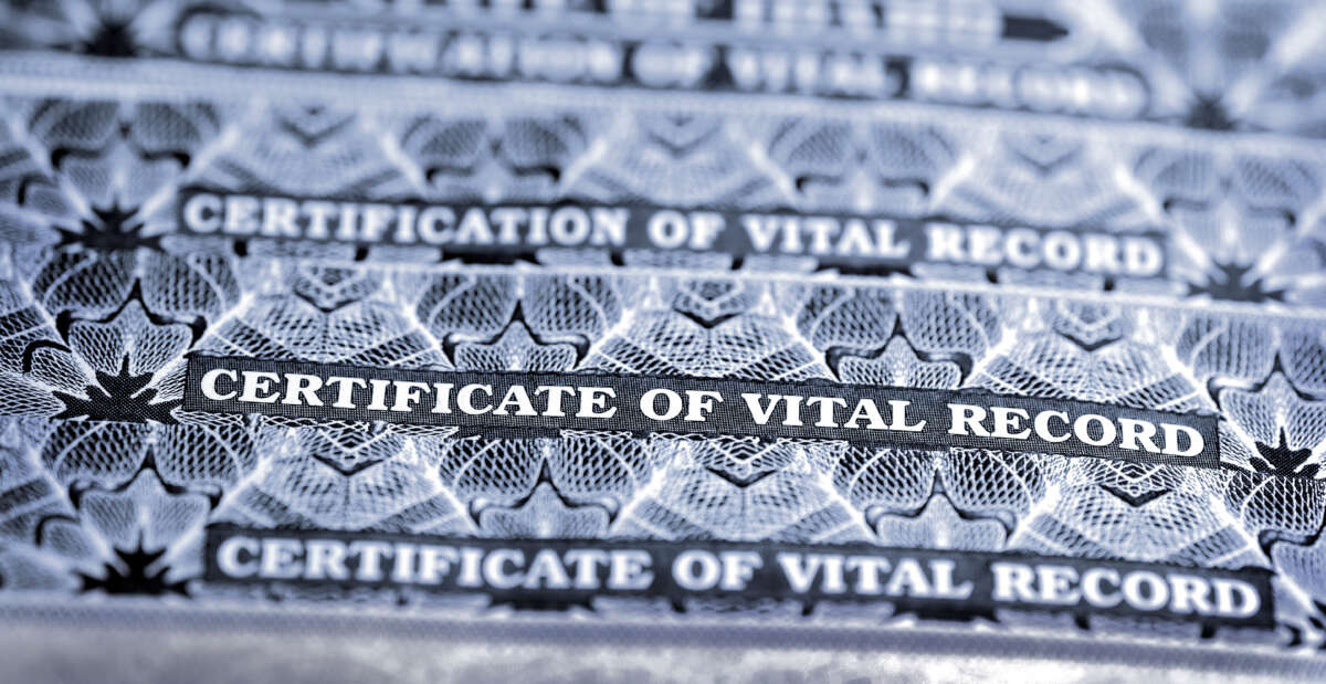 A stack of birth certificates marked 'Certificate of Vital Record'