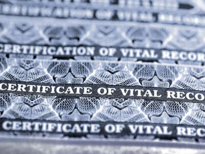 A stack of birth certificates marked 'Certificate of Vital Record'