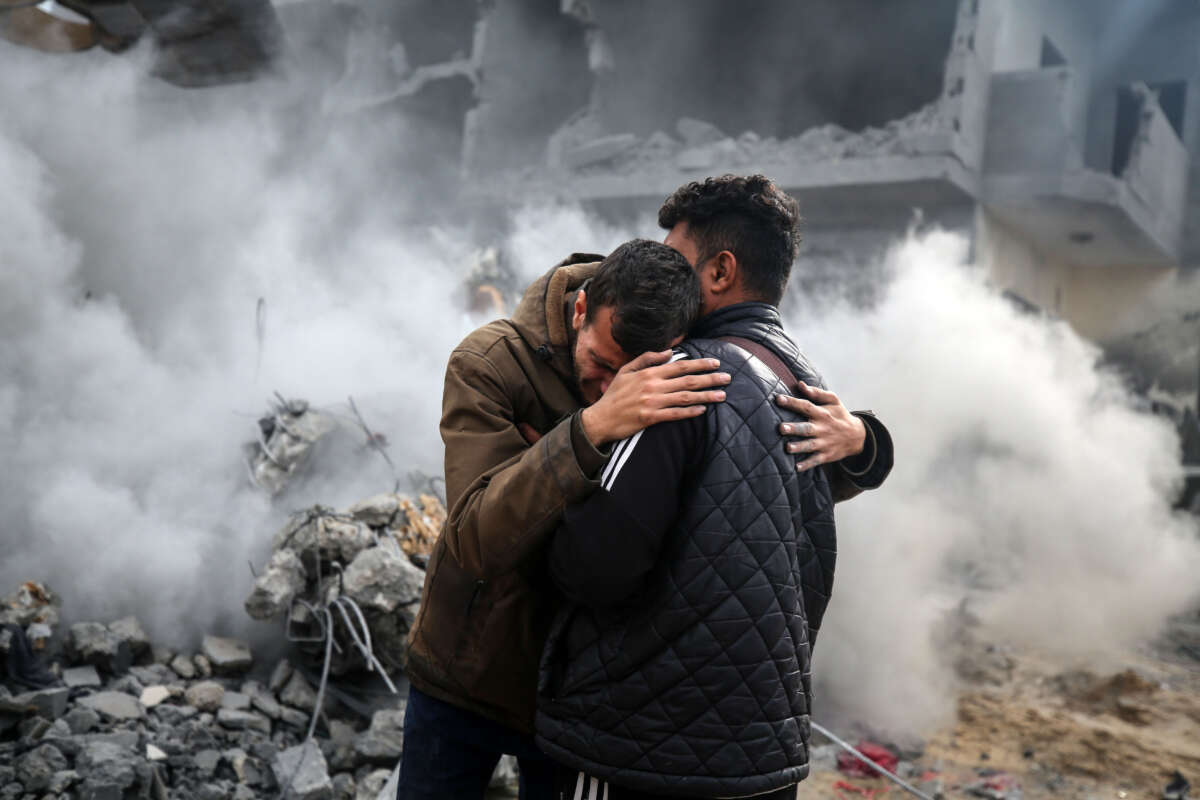 People mourn while standing in destruction caused by overnight Israeli bombardment in Deir Balah in the central Gaza Strip on February 23, 2024.