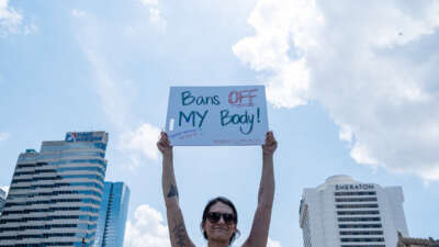 A protester holds a sign reading "BANS OFF MY BODY" during an outdoor protest