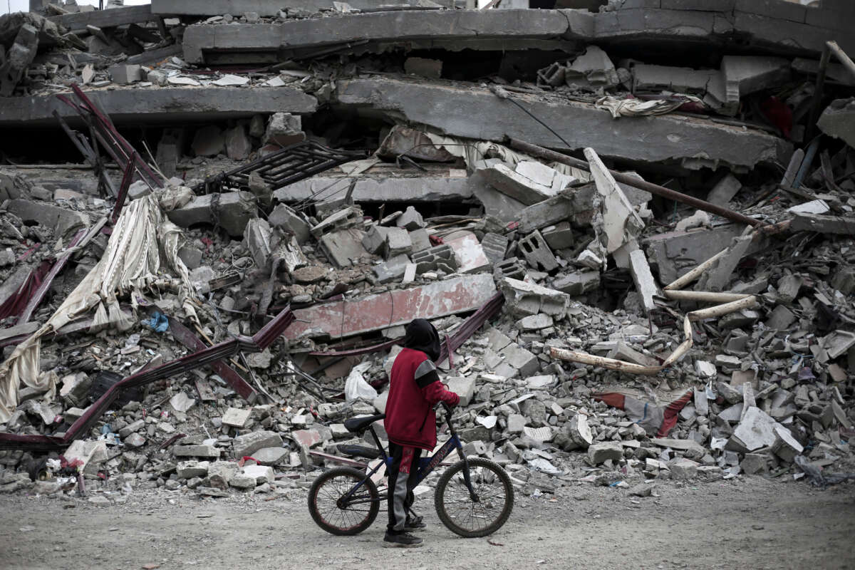 A Palestinian boy riding his bicycle looks at the rubble of a house destroyed by Israeli bombardment in Rafah in the southern Gaza Strip on February 27, 2024.