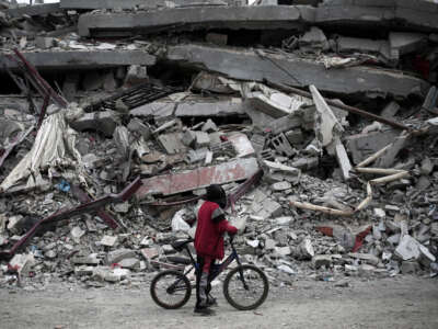 A Palestinian boy riding his bicycle looks at the rubble of a house destroyed by Israeli bombardment in Rafah in the southern Gaza Strip on February 27, 2024.