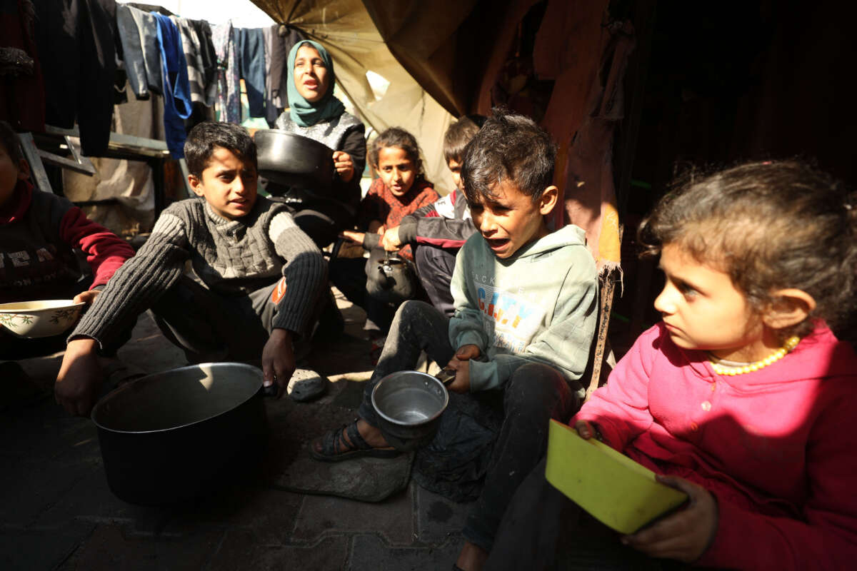 Palestinian children wait for the food with pots as Palestinian people survive under difficult conditions at Jabalia Refugee Camp in Gaza on February 26, 2024.