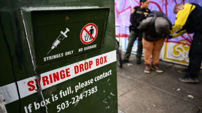 A syringe drop box stands on the street as a Portland Police officer conducts an investigation into drug dealing and issues a citation for drug possession during a patrol in downtown Portland, Oregon, on January 25, 2024.