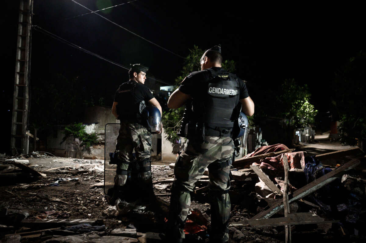 French gendarmes stand guard at night in front of demolished buildings in the shantytown of "Talus 2" district in Koungou, as part of Operation Wuambushu on the French Indian Ocean island of Mayotte, on May 25, 2023. Authorities in Mayotte are carrying out Operation Wuambushu ("Take Back" in the local language) to clear slums, demolishing the makeshift settlements and sending migrants back to neighboring Comoros.