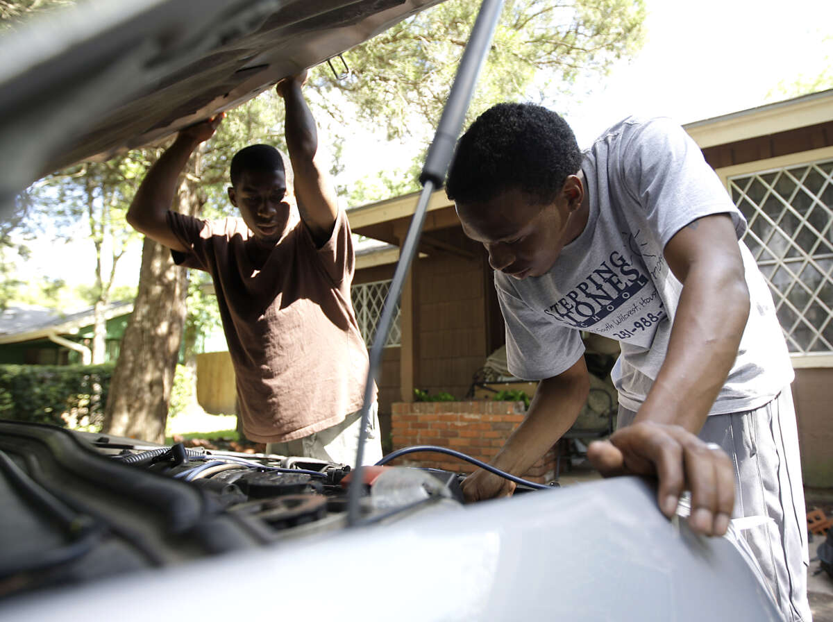 Everly James, who was formerly incarcerated and does odd jobs for money as he tries to find work, works on the air conditioning system of Lindsey Turner's car on June 23, 2011, in Houston, Texas.