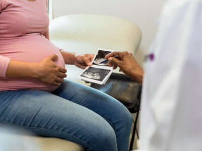 Pregnant woman holding ultrasound pictures
