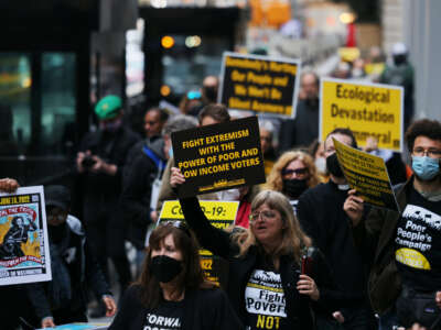 Protesters hold signs saying "fight extremism with the power of poor and low-income voters"