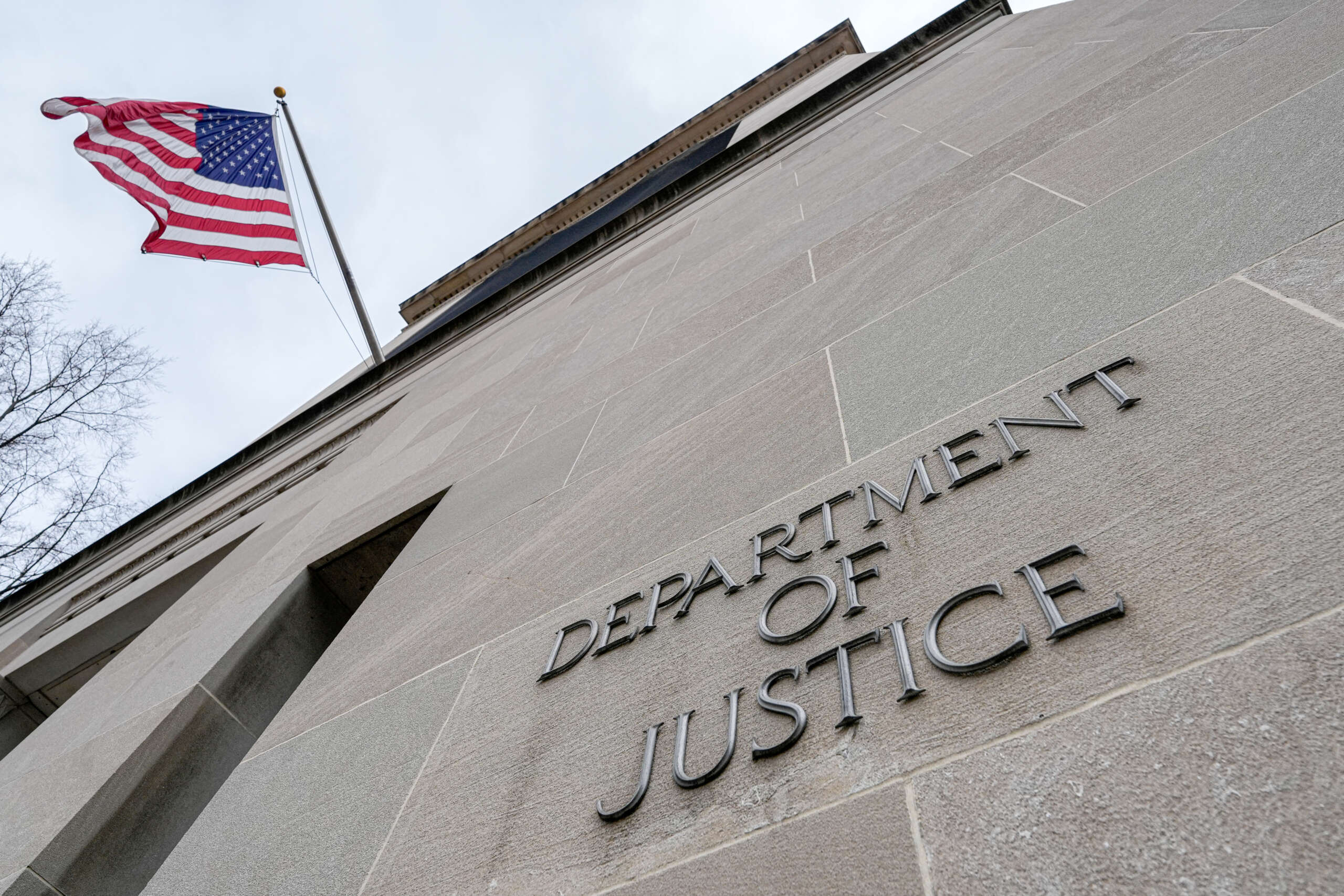 The U.S. Flag flies above a sign marking the Department of Justice headquarters building on January 20, 2024, in Washington, D.C.