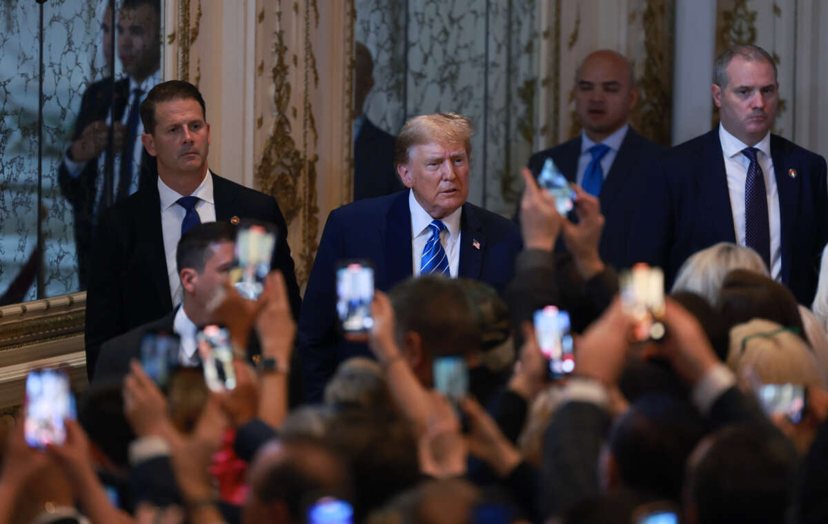 Donald trump looks at a group of people taking photos of him with their phones