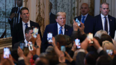 Donald trump looks at a group of people taking photos of him with their phones