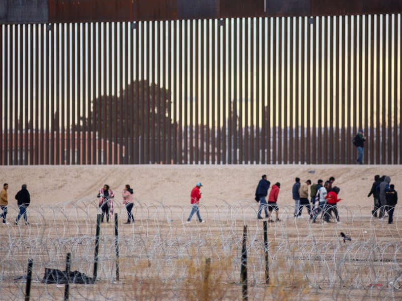 People walk along the border wall at the U.S./Mexico border