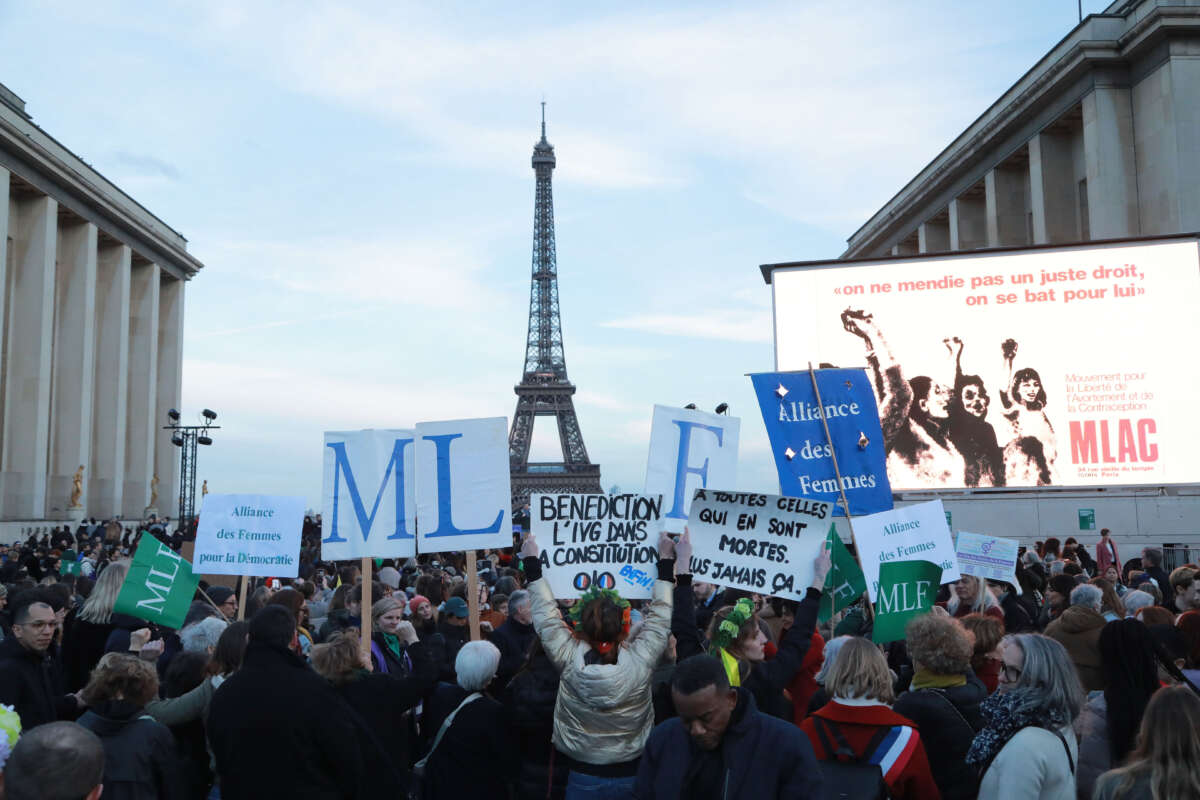 Demonstrators, holding banners, demand the inclusion of the right to abortion in the constitution gather for women's rights rally in front of a giant screen to follow the debate on the single-article draft law near Eiffel Tower in Trocadero, Paris, France, on March 4, 2024.