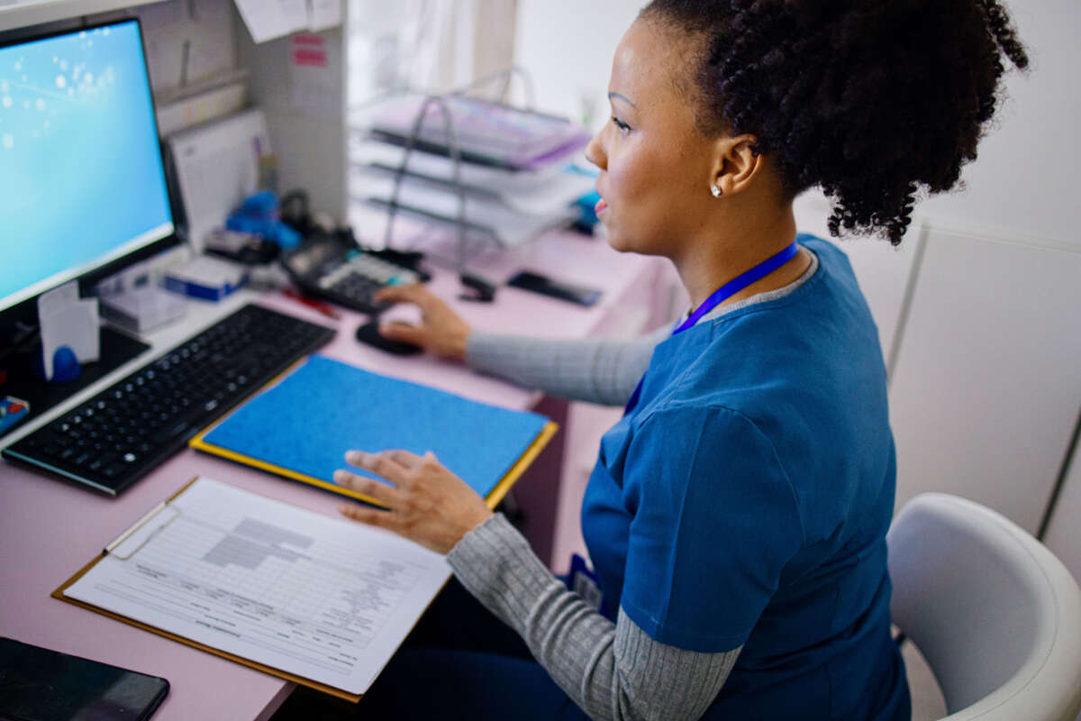 Health care worker checks file on computer