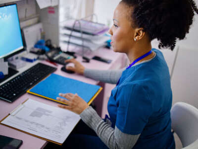 Health care worker checks file on computer