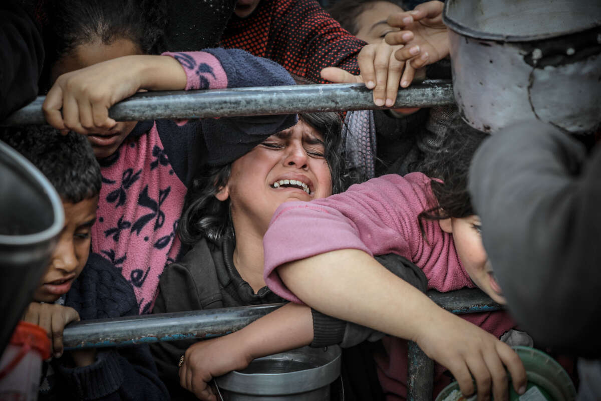 Palestinian children wait in line to receive food prepared by volunteers for Palestinian families, displaced to southern Gaza due to Israeli attacks, in Rafah, Gaza, on February 10, 2024.