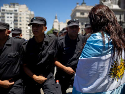 A woman covered with an Argentine flag takes part in a demonstration outside the Argentine Congress during a national strike against the government of Javier Milei in Buenos Aires, on January 24, 2024.