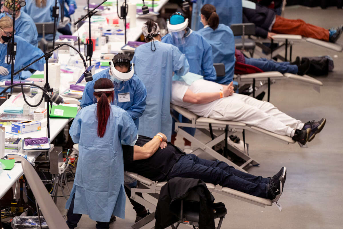 People receive dental care in a large open area resembling a gymnasium