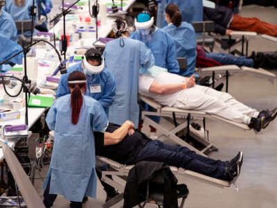 People receive dental care in a large open area resembling a gymnasium
