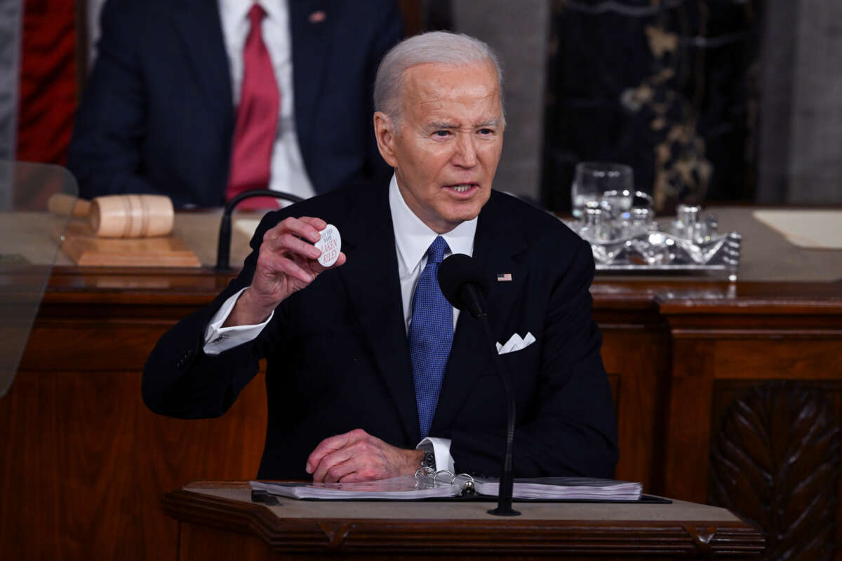 Joe Biden holds up a button reading "Laken Rikey"