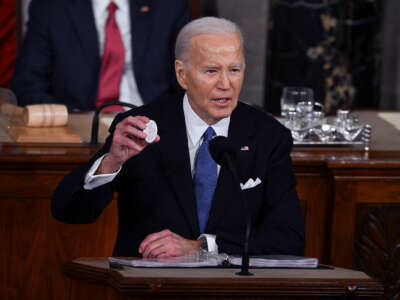 Joe Biden holds up a button reading "Laken Rikey"