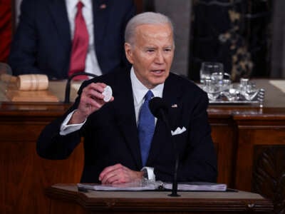 Joe Biden holds up a button reading "Laken Rikey"