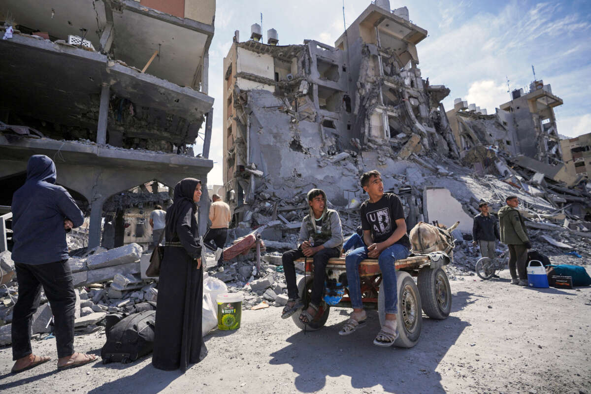 Displaced Palestinians, along with their belongings, gather in a street amid the rubble of houses destroyed by Israeli bombardment in the Hamad area west of Khan Yunis in the southern Gaza Strip on March 14, 2024.