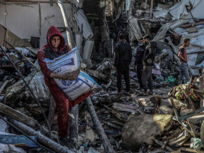 A Palestinian child takes a bag of flour from a destroyed house after an Israeli air strike, on March 8, 2024, in the city of Rafah in the southern Gaza Strip.