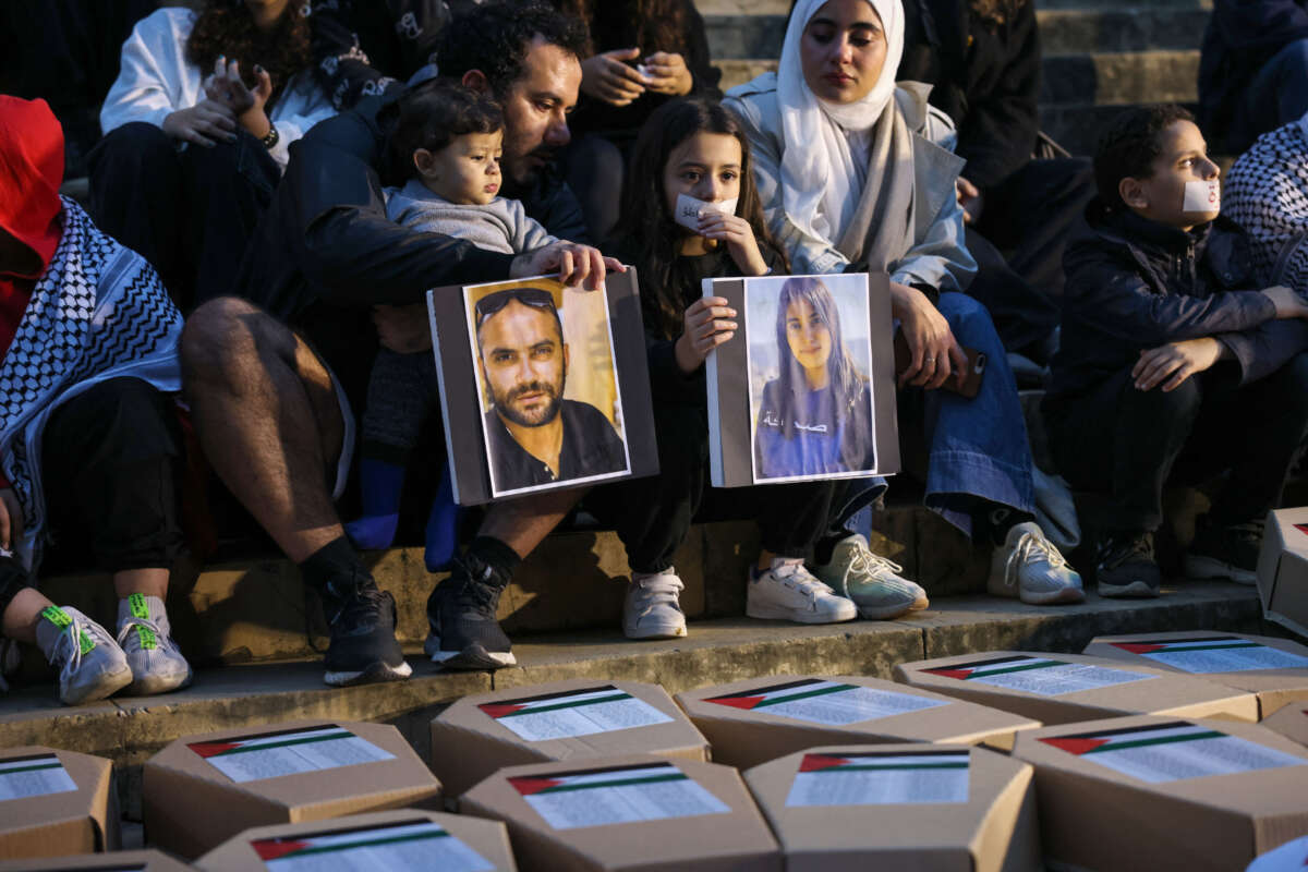 Demonstrators lift portraits of Reuters journalist Issam Abdallah (left) and Al-Mayadeen TV reporter Farah Omar, killed in separate instances while covering the frequent exchanges of fire across Lebanon's border with Israel, while sitting in front of symbolic coffins and shrouds of children at a rally supporting Gaza in front of the National Museum building in Beirut on December 8, 2023.