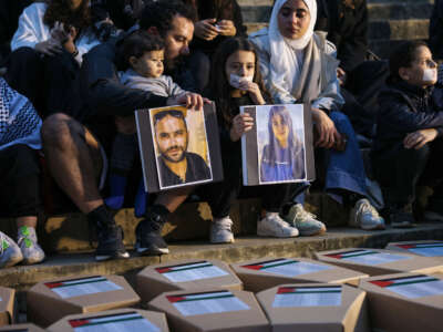 Demonstrators lift portraits of Reuters journalist Issam Abdallah (left) and Al-Mayadeen TV reporter Farah Omar, killed in separate instances while covering the frequent exchanges of fire across Lebanon's border with Israel, while sitting in front of symbolic coffins and shrouds of children at a rally supporting Gaza in front of the National Museum building in Beirut on December 8, 2023.
