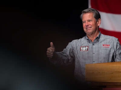 Brian Kemp smiles awkwardly as he gives a thumbs up