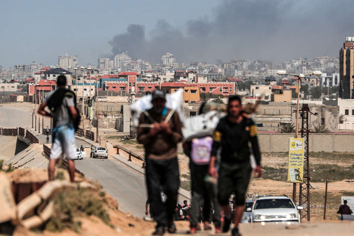 Smoke rises above buildings during Israeli bombardment as people fleeing the Al-Shifa hospital compound and its vicinity in Gaza City, reach the central part of the Gaza Strip on March 21, 2024.