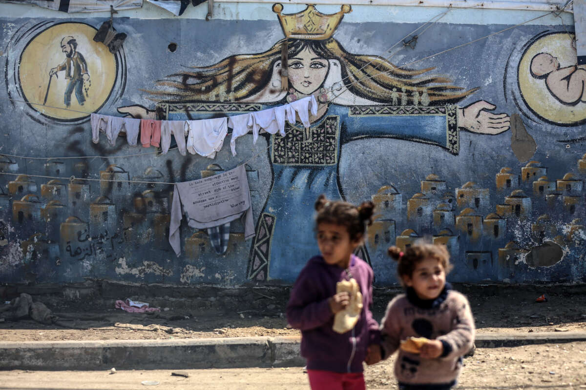Palestinians are walking in front of a mural at an UNRWA school in Deir Al-Balah, Central Gaza Strip, on March 8, 2024.