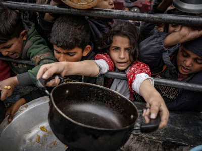 Palestinian children, holding empty pots, wait in line to receive food prepared by volunteers for Palestinian families displaced to Southern Gaza due to Israeli attacks, in Rafah, Gaza, on February 10, 2024.