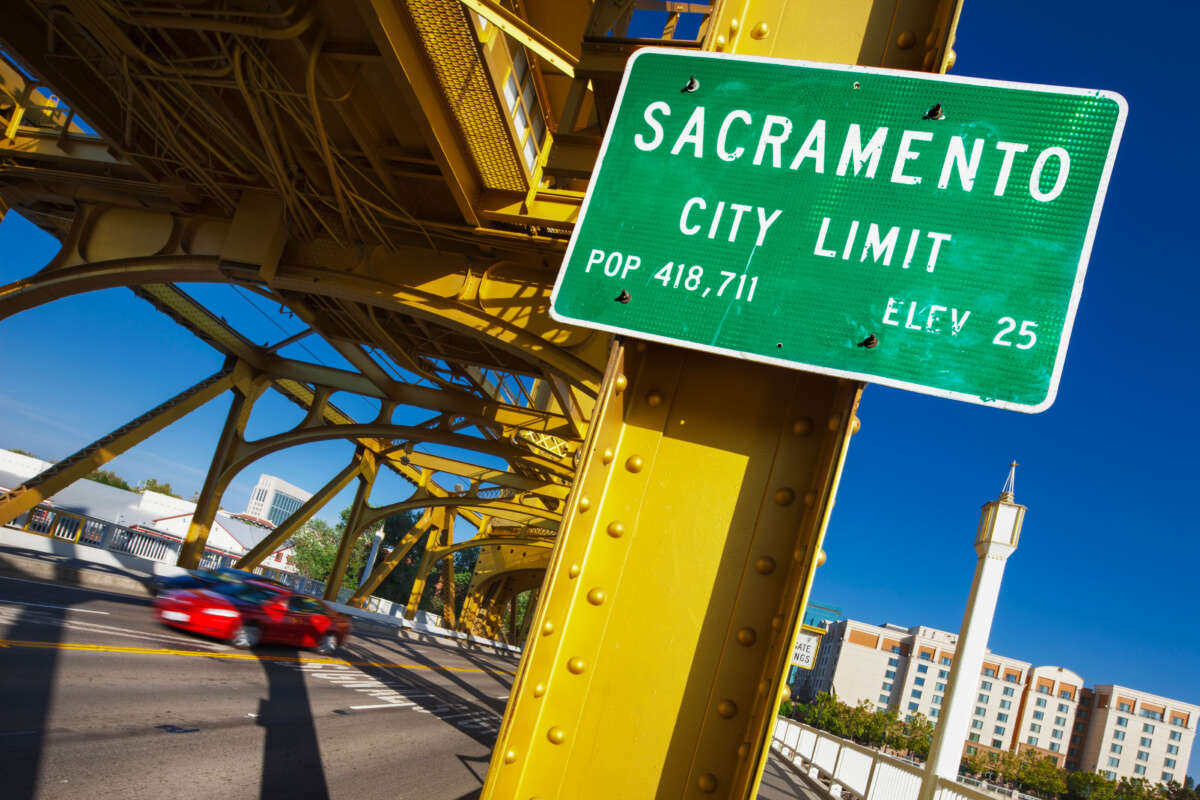 Sacramento city limit sign attached to yellow bridge structure on clear blue day