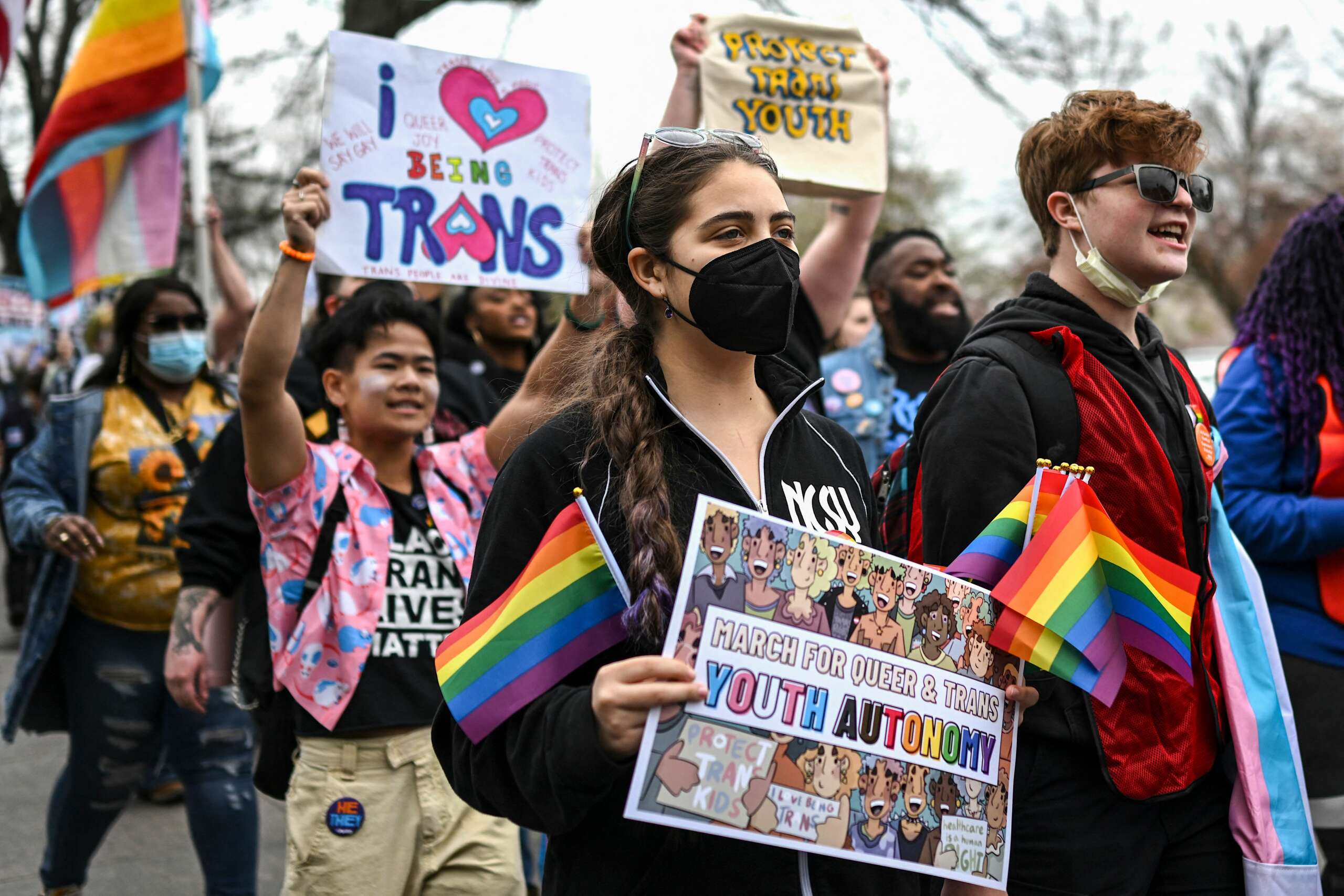 Protesters holds rainbow flags and signs supporting trans rights