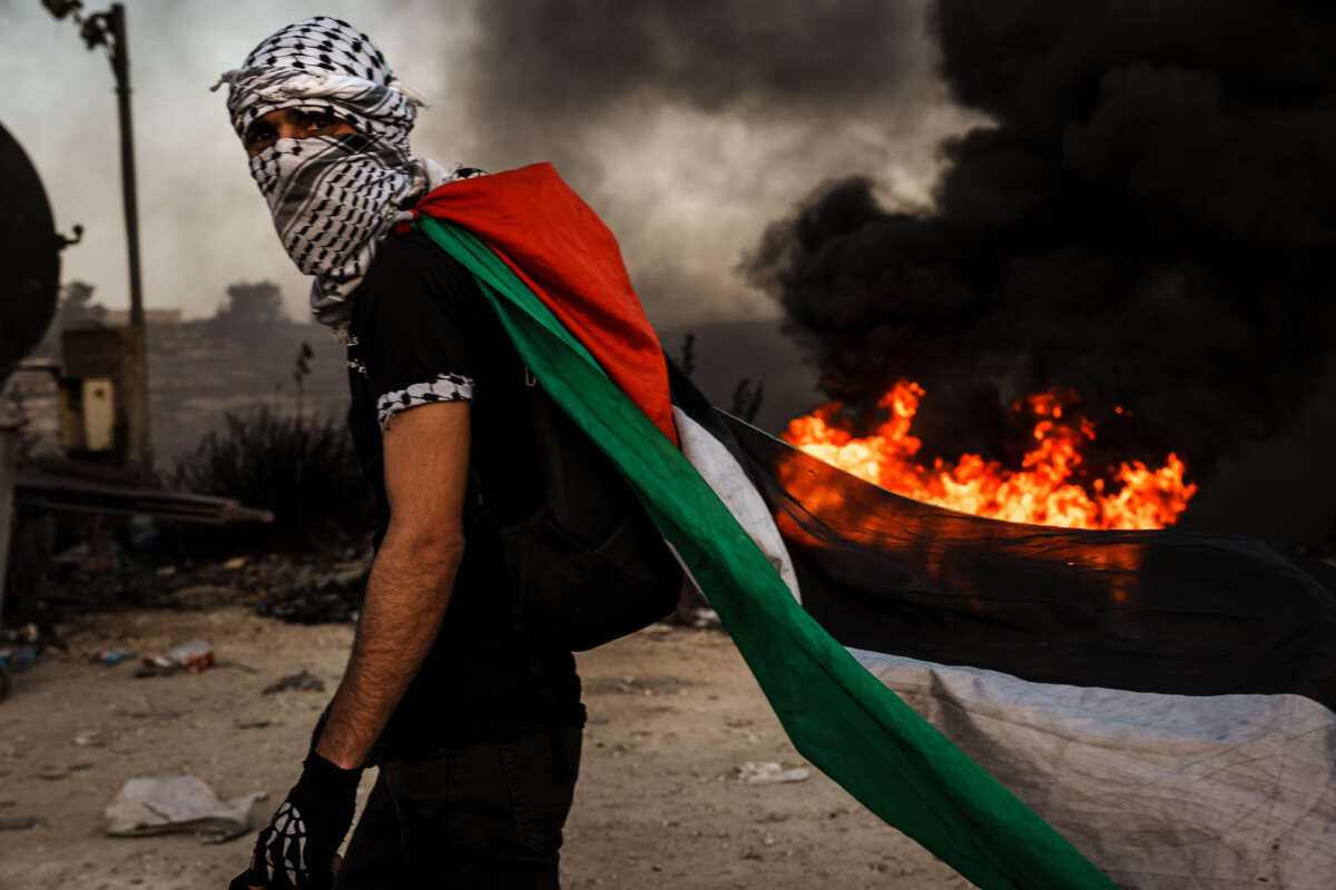 A Palestinian dons a Palestinian flag during while protesting the Israeli occupation in the West Bank, as protesters are met with tear gas, flashbangs and live fire from Israeli forces, in Ramallah, Palestine, on October 13, 2023.