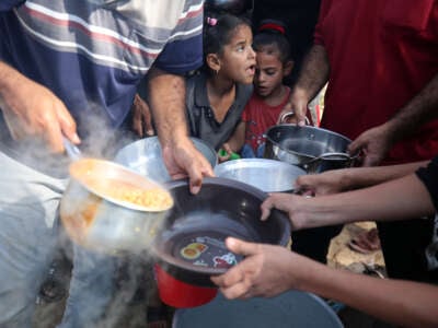Palestinian children receive food at refugee center in Gaza