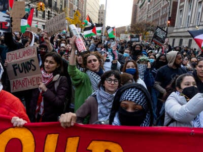 Pro-Palestine student demonstrators wave flags and wear keffiyehs at a march in New York City