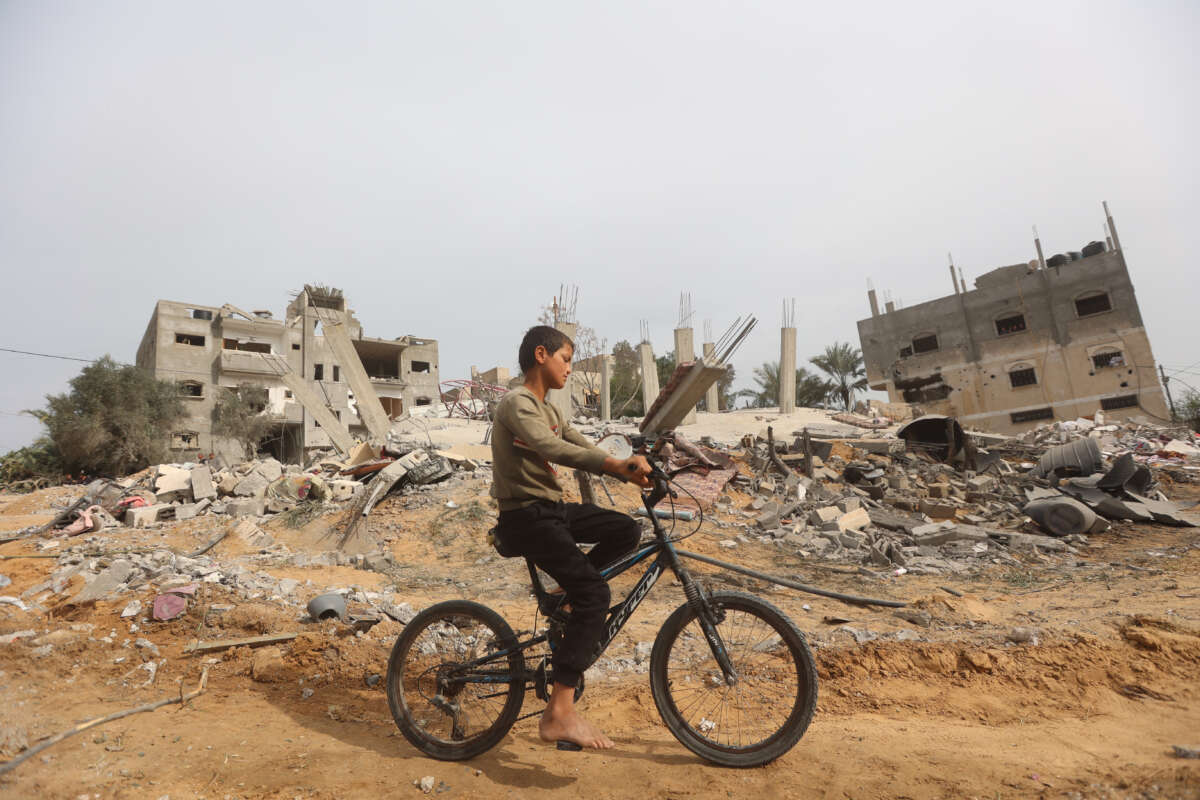 A child bikes by a destroyed building after an Israeli airstrike in Khan Yunis, Gaza, on March 29, 2024.