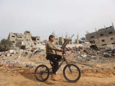 A child bikes by a destroyed building after an Israeli airstrike in Khan Yunis, Gaza, on March 29, 2024.