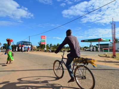 A man cycles past a gas station in Mozambique