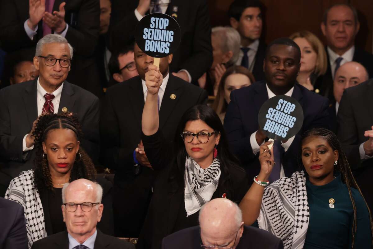 Rep. Rashida Tlaib (D-Michigan) (C) and Rep. Cori Bush (D-Missouri) hold up signs as President Joe Biden delivers the State of the Union address during a joint meeting of Congress in the House chamber at the U.S. Capitol on March 07, 2024.