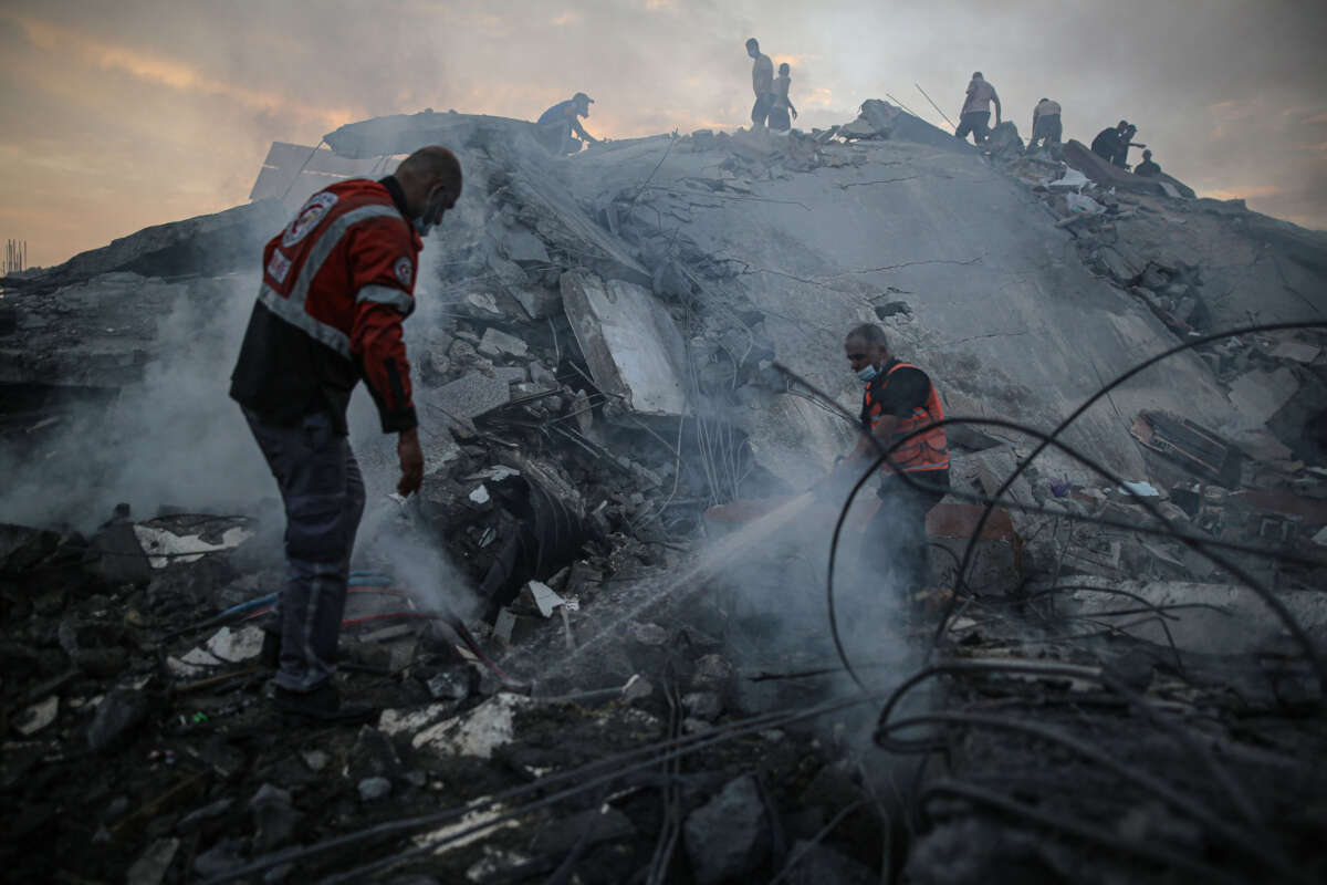 Teams extinguish a fire as they conduct a search and rescue operation under the debris of destroyed building following Israeli attacks on the Nuseirat Camp in Deir al Balah, Gaza, on October 31, 2023.