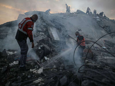 Teams extinguish a fire as they conduct a search and rescue operation under the debris of destroyed building following Israeli attacks on the Nuseirat Camp in Deir al Balah, Gaza, on October 31, 2023.