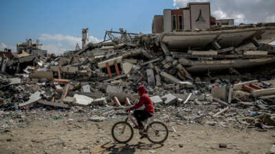 A man rides his bicycle past the al-Aqsa University, leveled by Israeli bombardment in Gaza City on February 15, 2024.