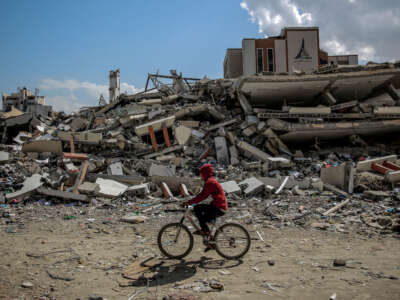 A man rides his bicycle past the al-Aqsa University, leveled by Israeli bombardment in Gaza City on February 15, 2024.