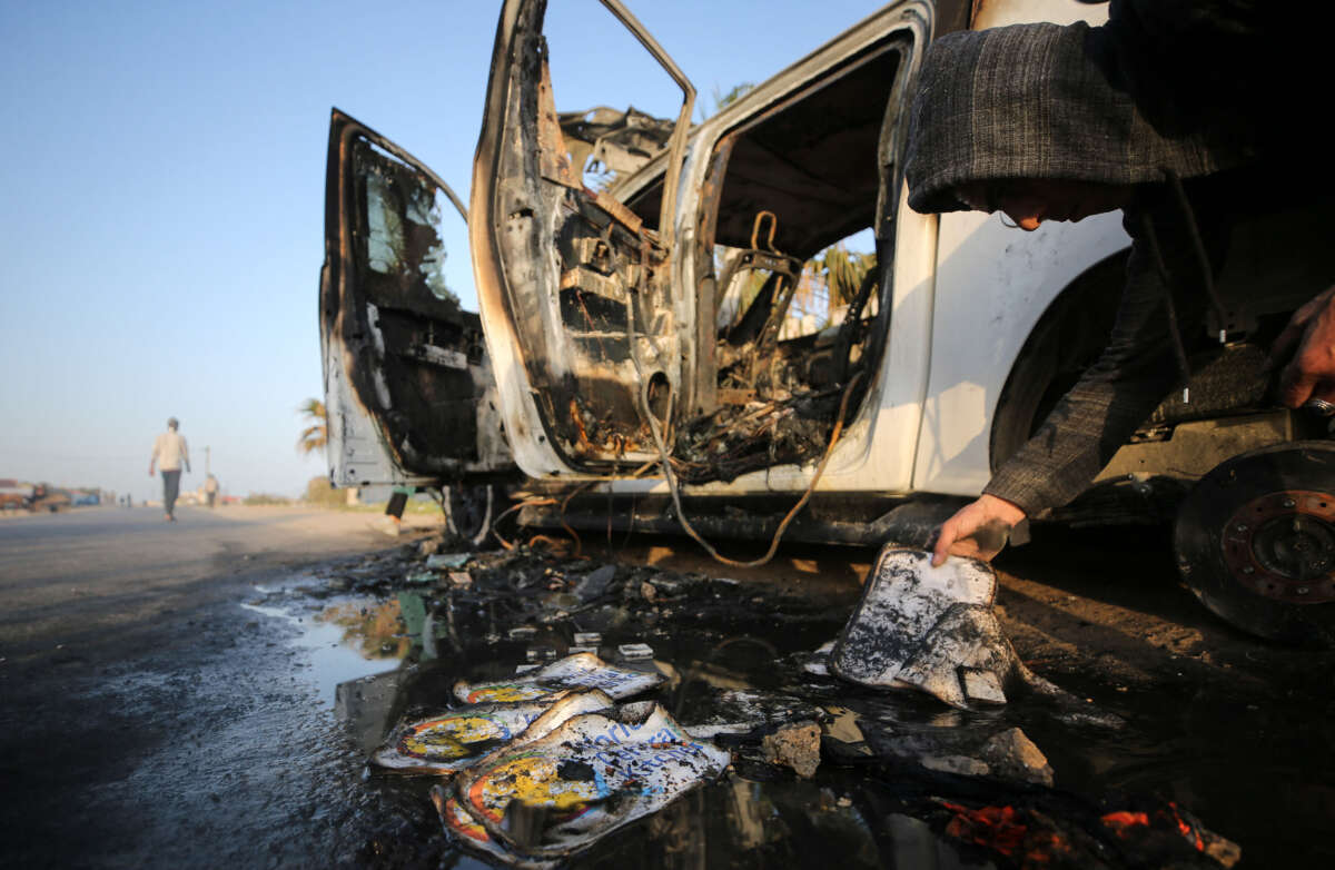 A Palestinian inspects near a vehicle where employees from the World Central Kitchen were killed in an Israeli airstrike, in Deir Al-Balah, in the central Gaza Strip, on April 2, 2024.