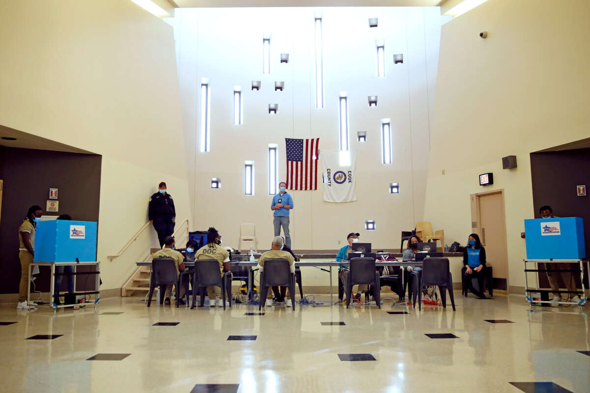 Prisoners vote in an open room with a US flag hanging from a far wall