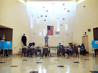 Prisoners vote in an open room with a US flag hanging from a far wall